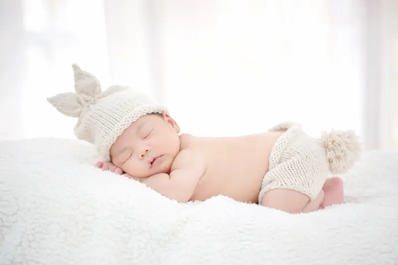 Bayi tidur nyenyak di tempat tidur putih